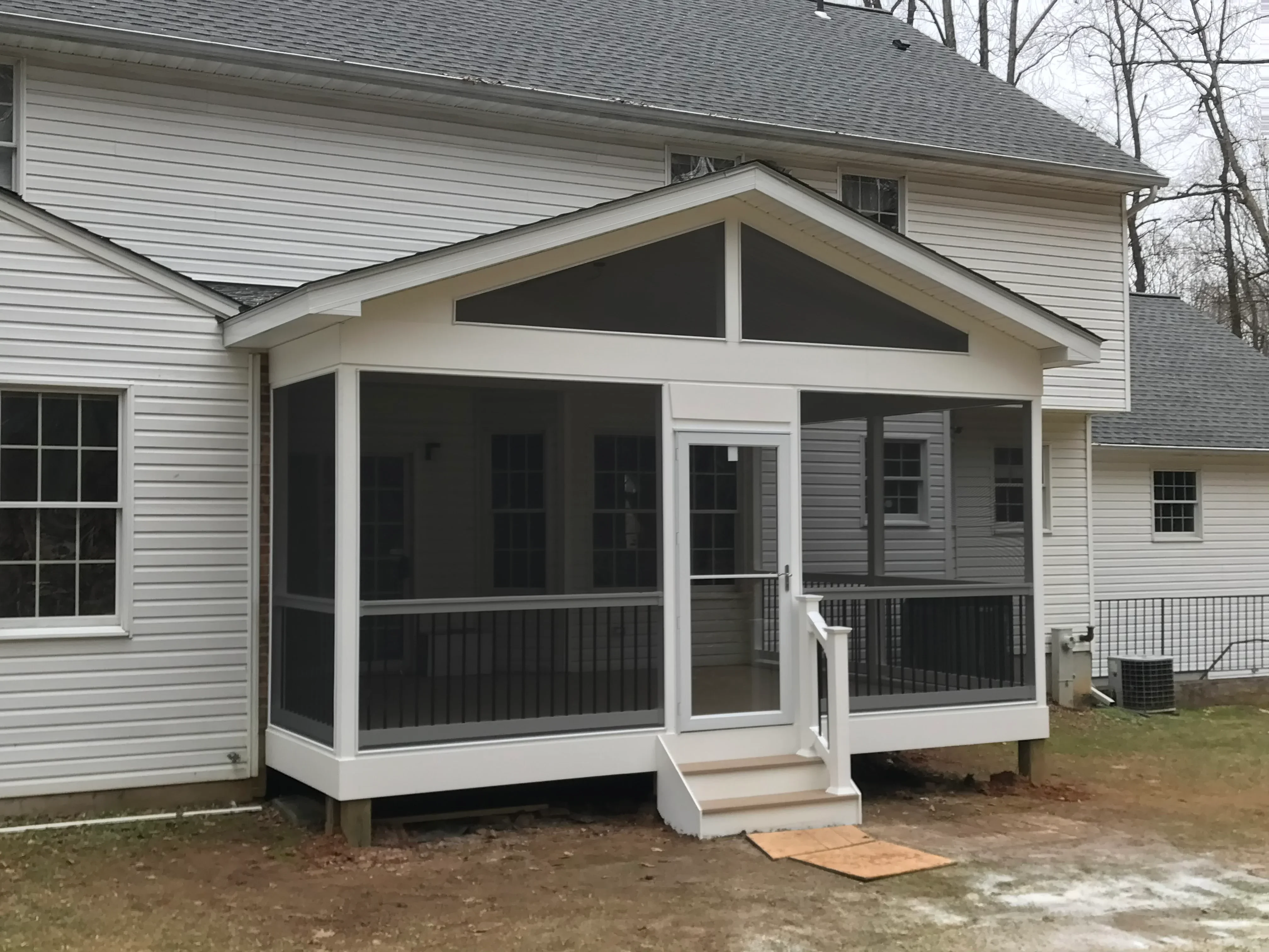 White vinyl screened porch with black screening, gable roof, and composite deck