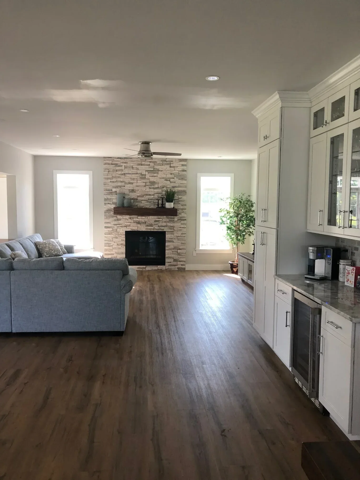 Modern living room with wood flooring, tile accent wall, coffered ceiling, and recessed lighting