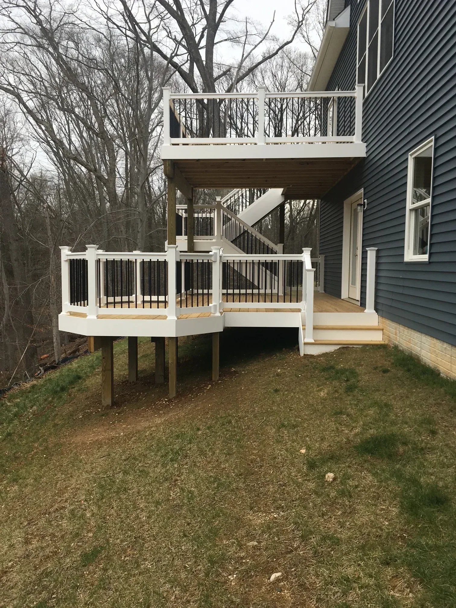 White composite deck with metal X-railings and pergola attached to metal-roofed structure
