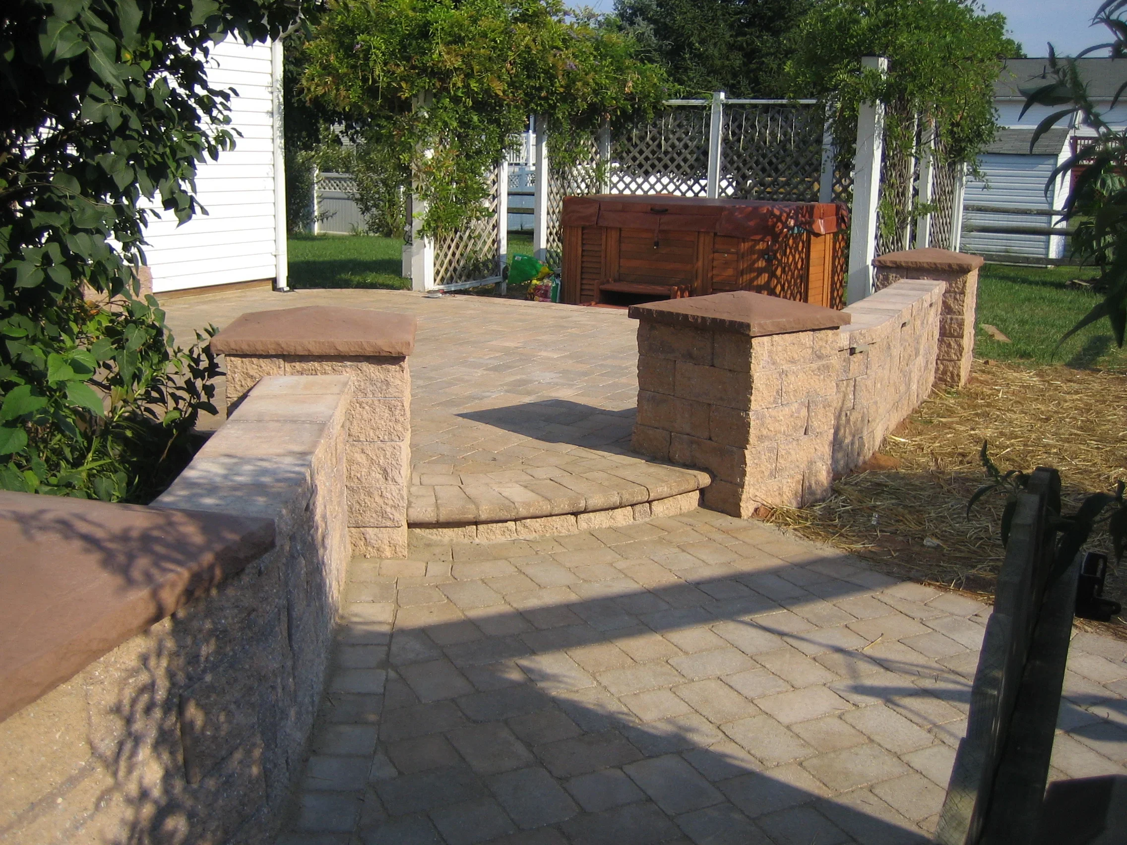 Stone patio with integrated seating walls and pillars, permeable pavers throughout