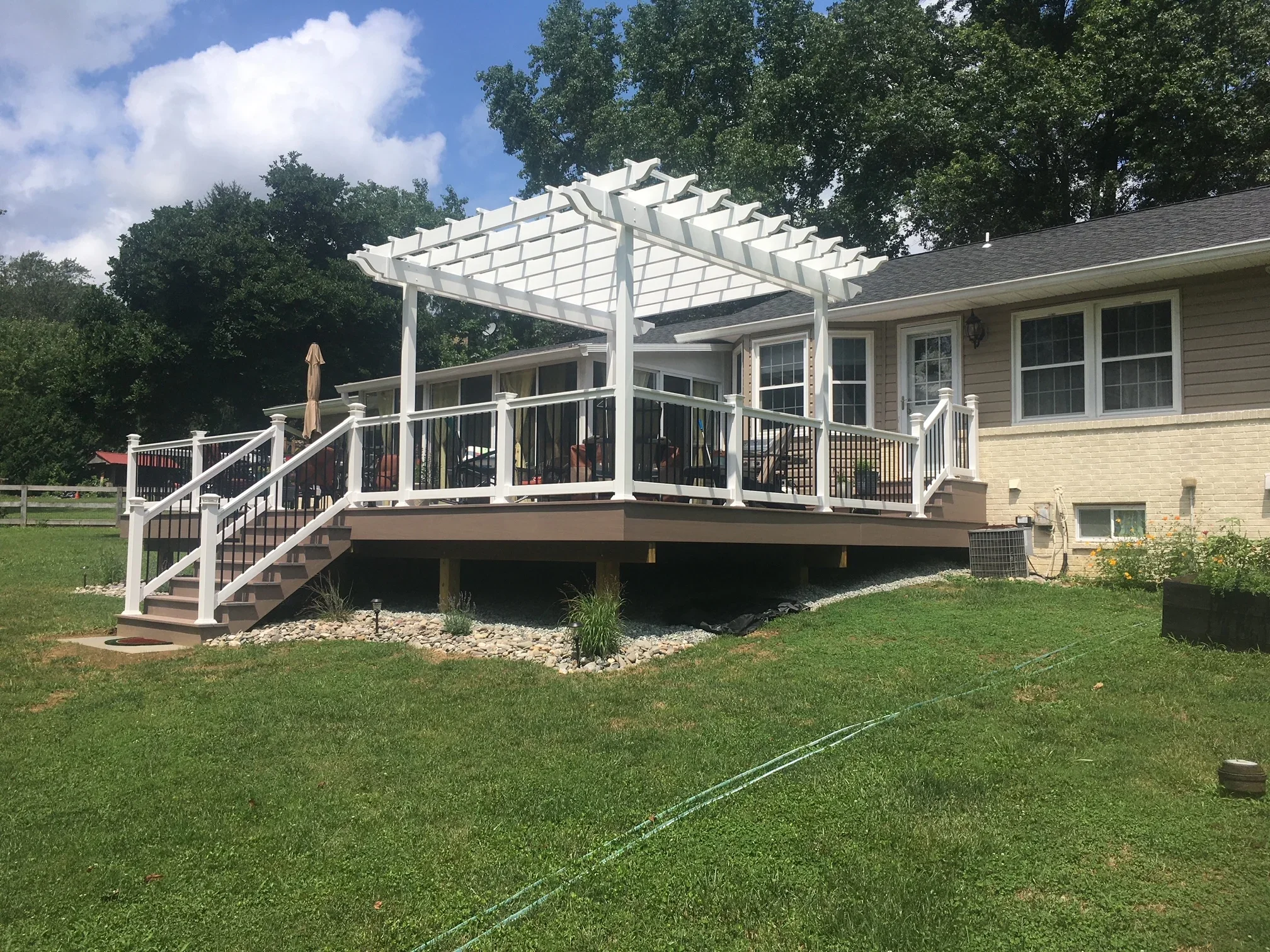 White composite deck with pergola, vinyl railings, and stairs attached to brick home