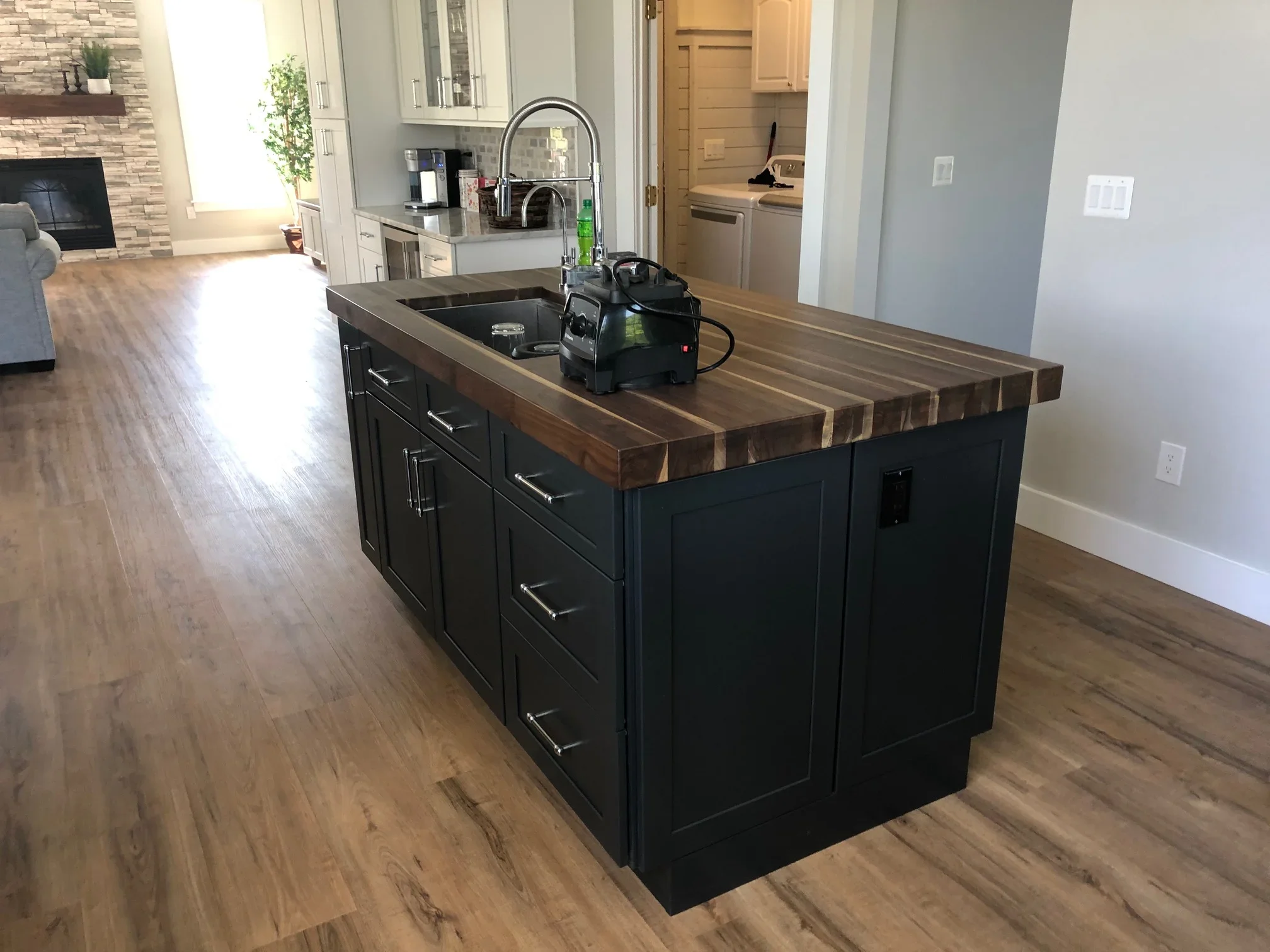 Black kitchen island with walnut butcher block countertop and undermount sink