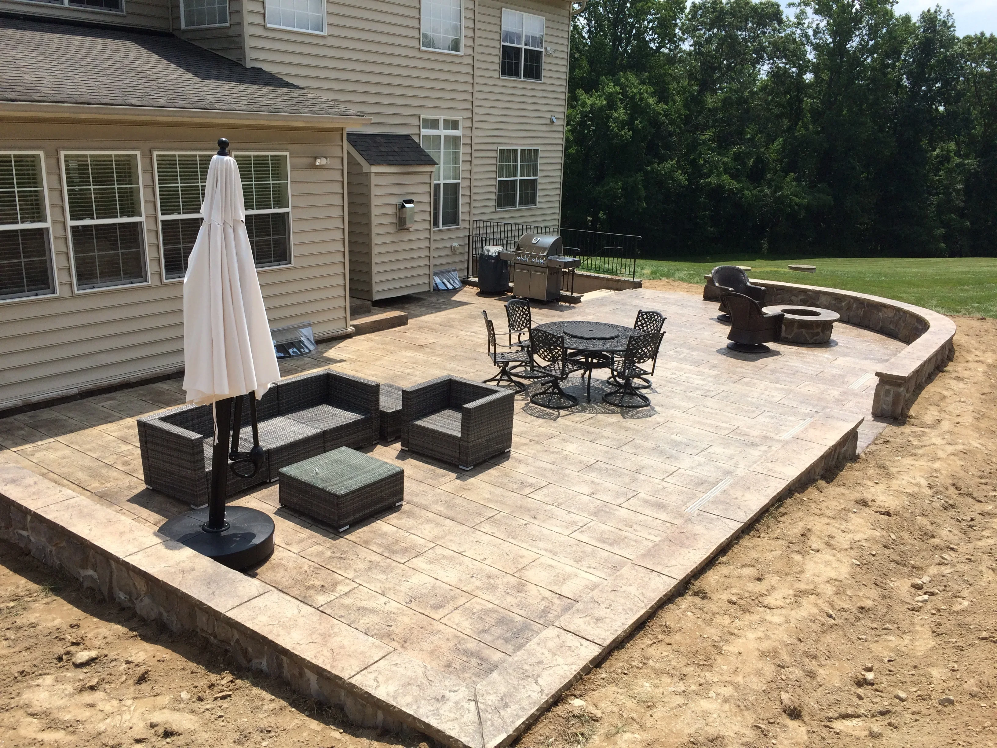 Stamped concrete patio with retaining walls, fire pit, and dining furniture