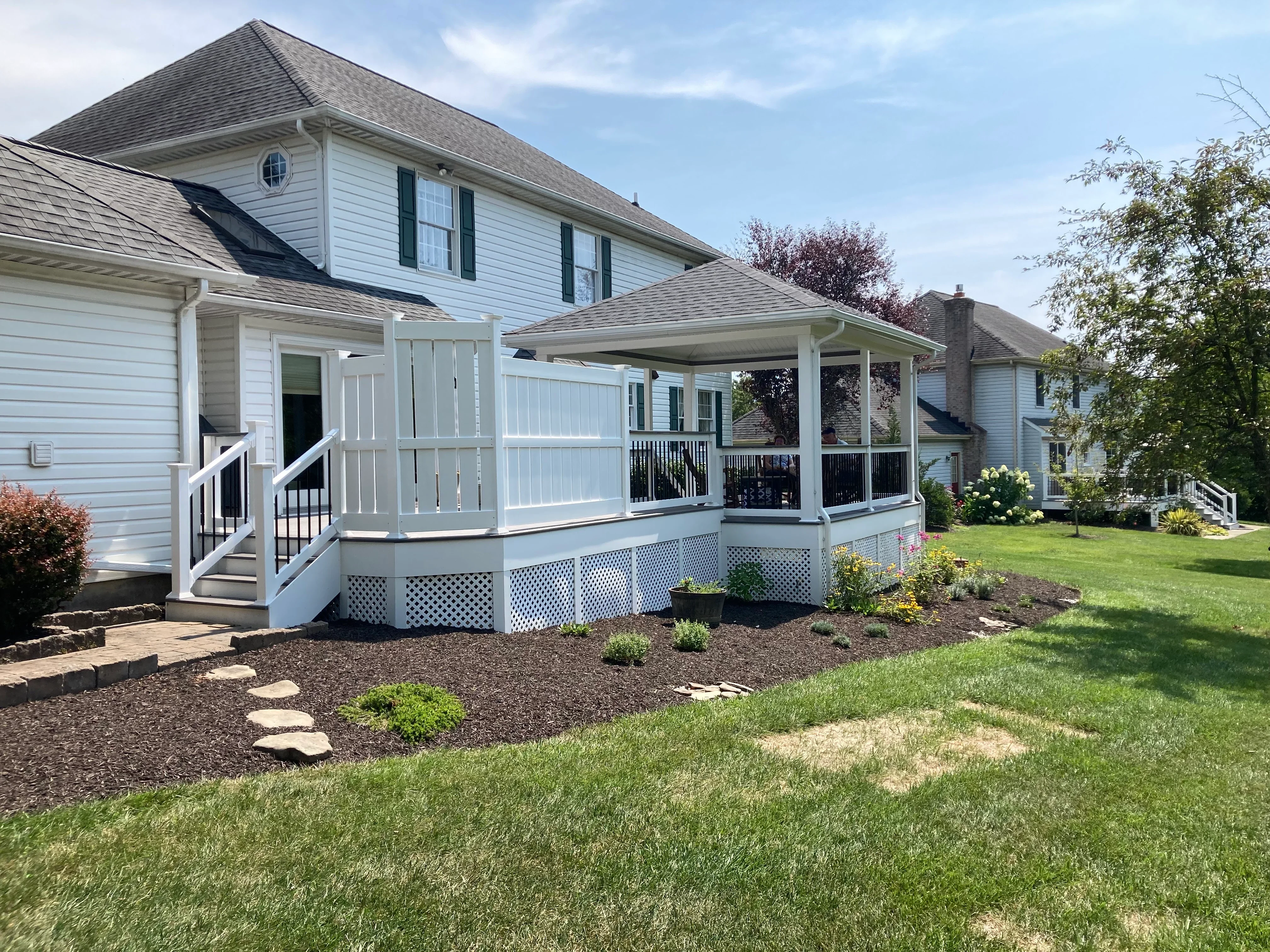 White composite deck with covered porch, vinyl railings, and lattice skirting on residential home