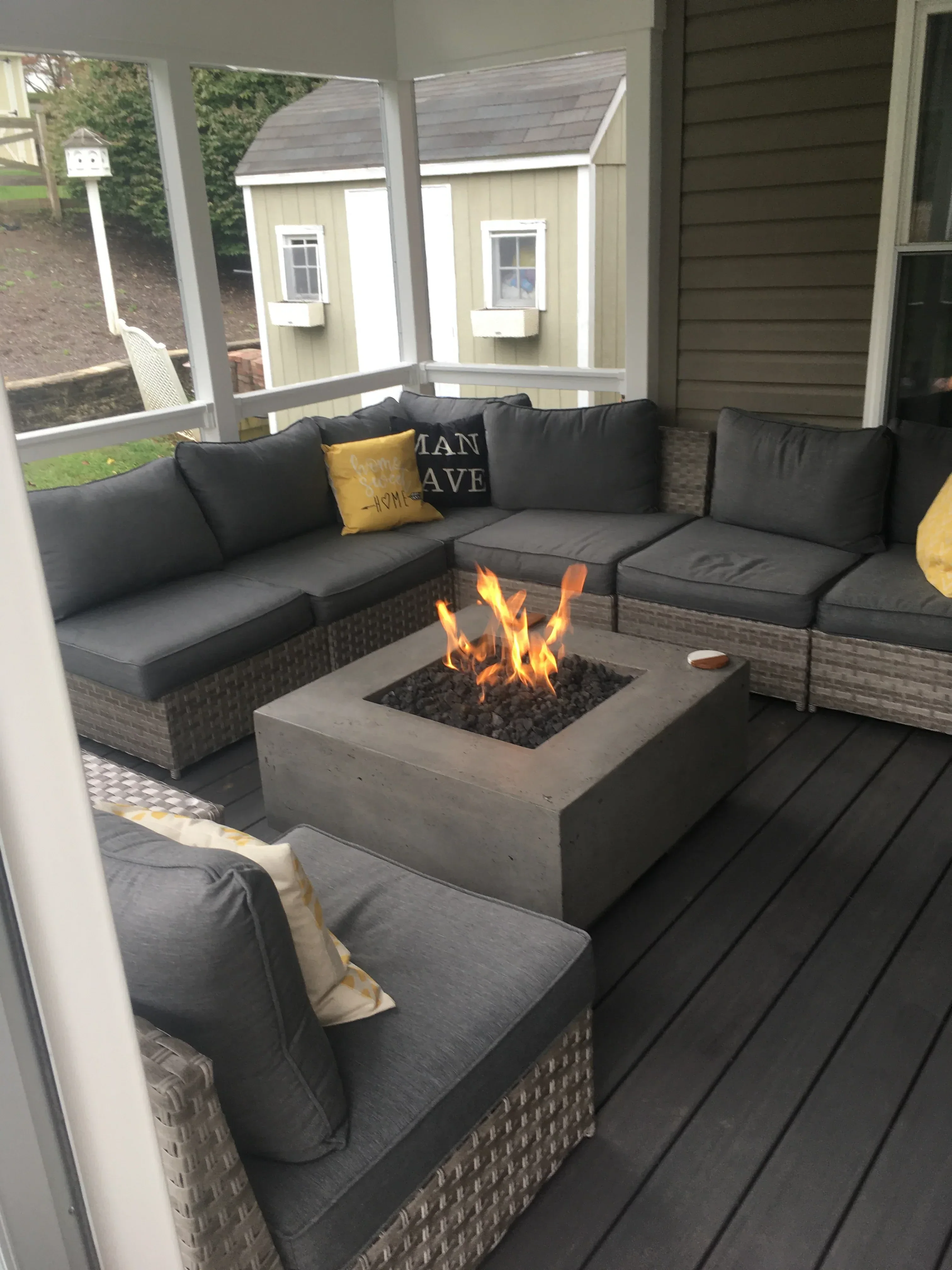 Composite deck patio with built-in fire pit, metal seating walls, and cushioned outdoor furniture