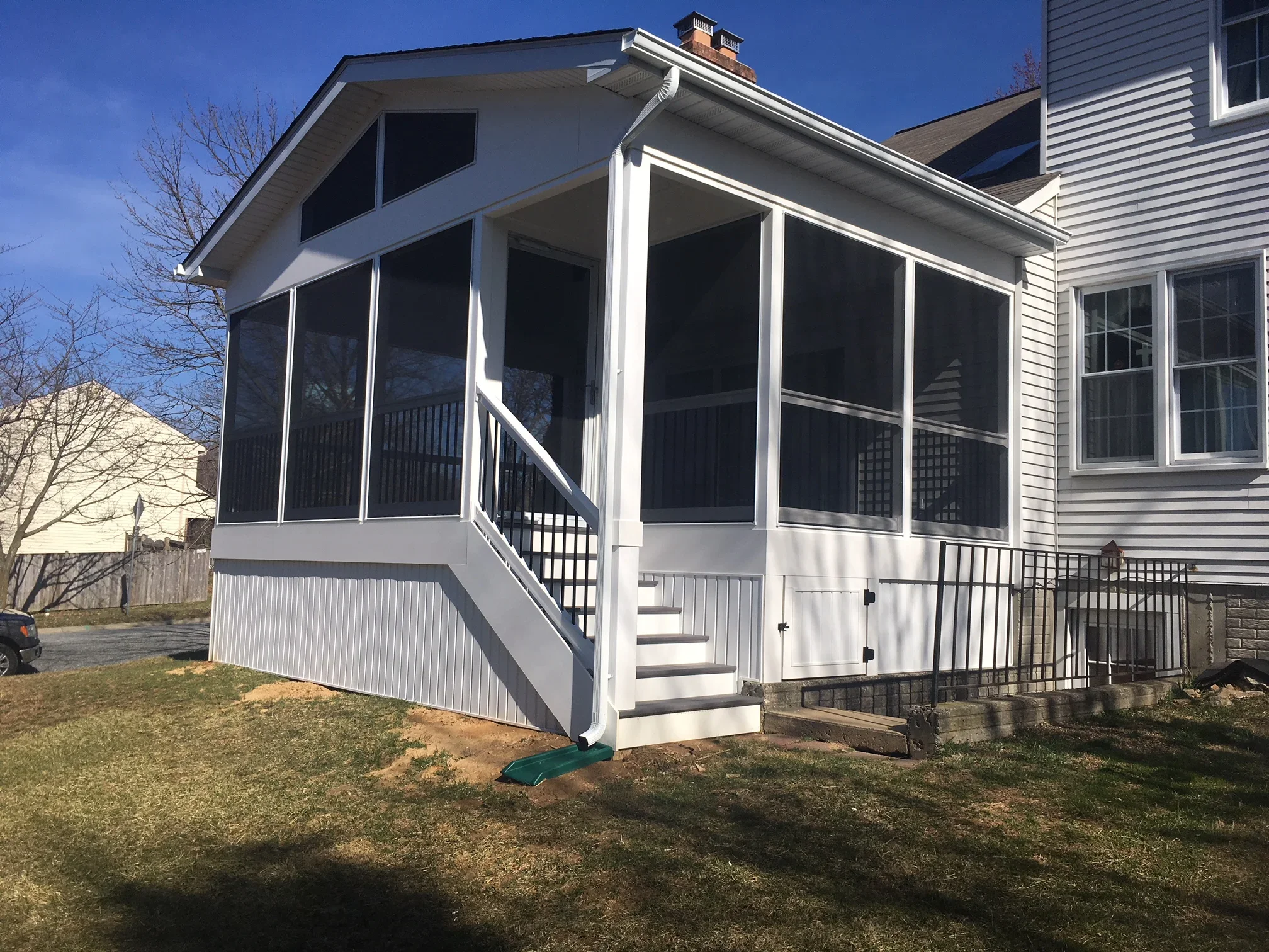 White screened room addition with black mesh screens, composite deck, and metal railings