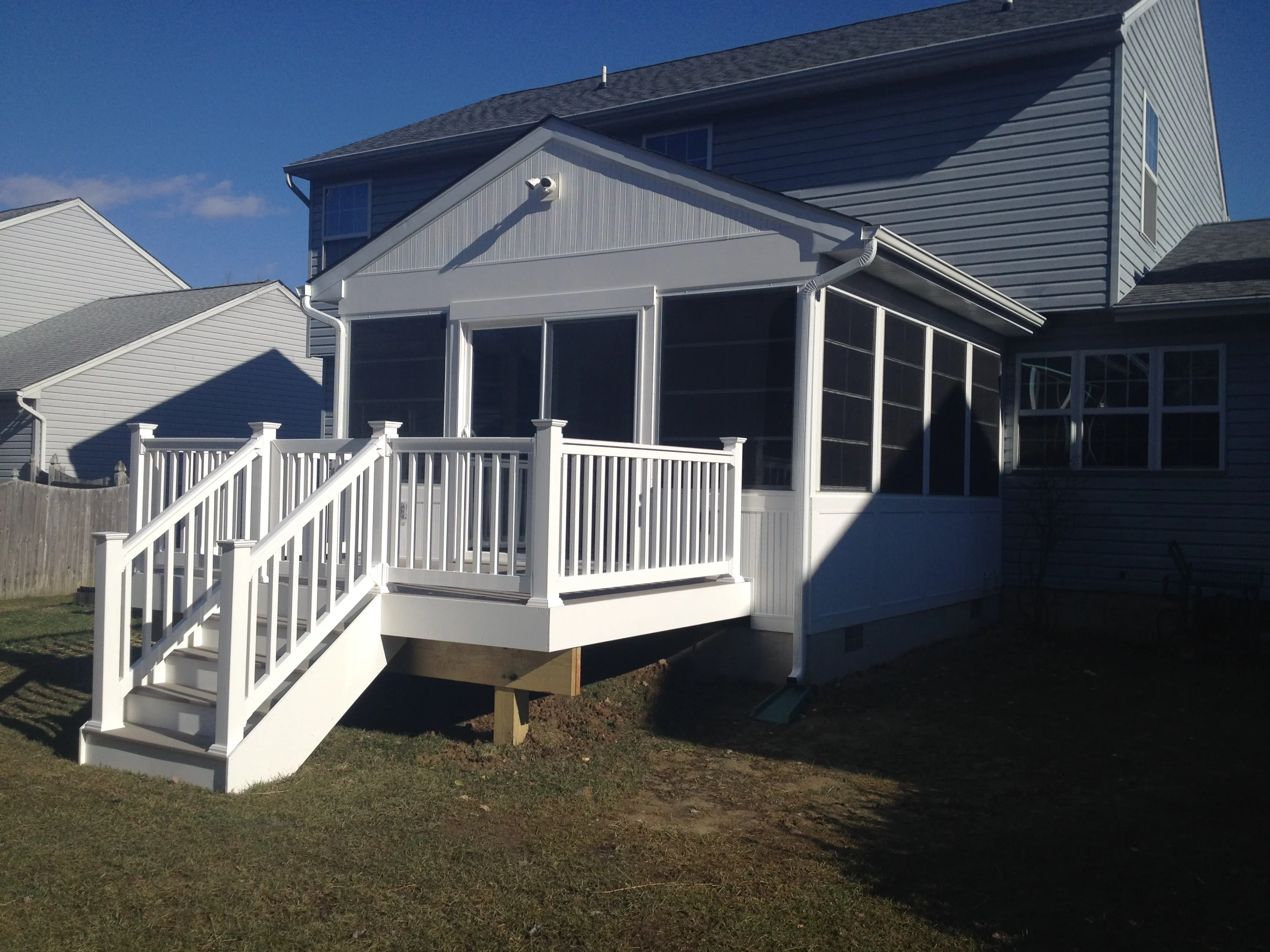 White vinyl sunroom with multi-pane windows, composite deck, and white vinyl railings