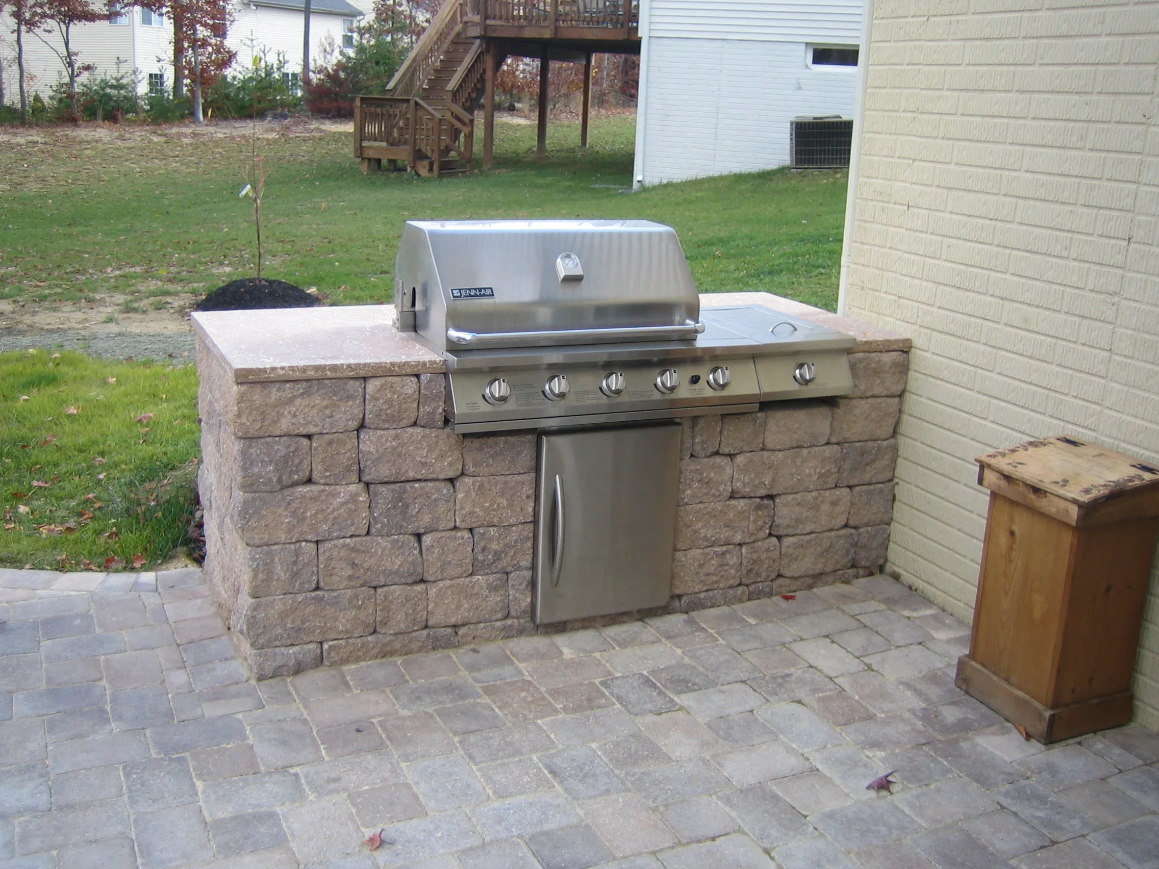 Stacked stone grill island with stainless steel gas grill and paver patio