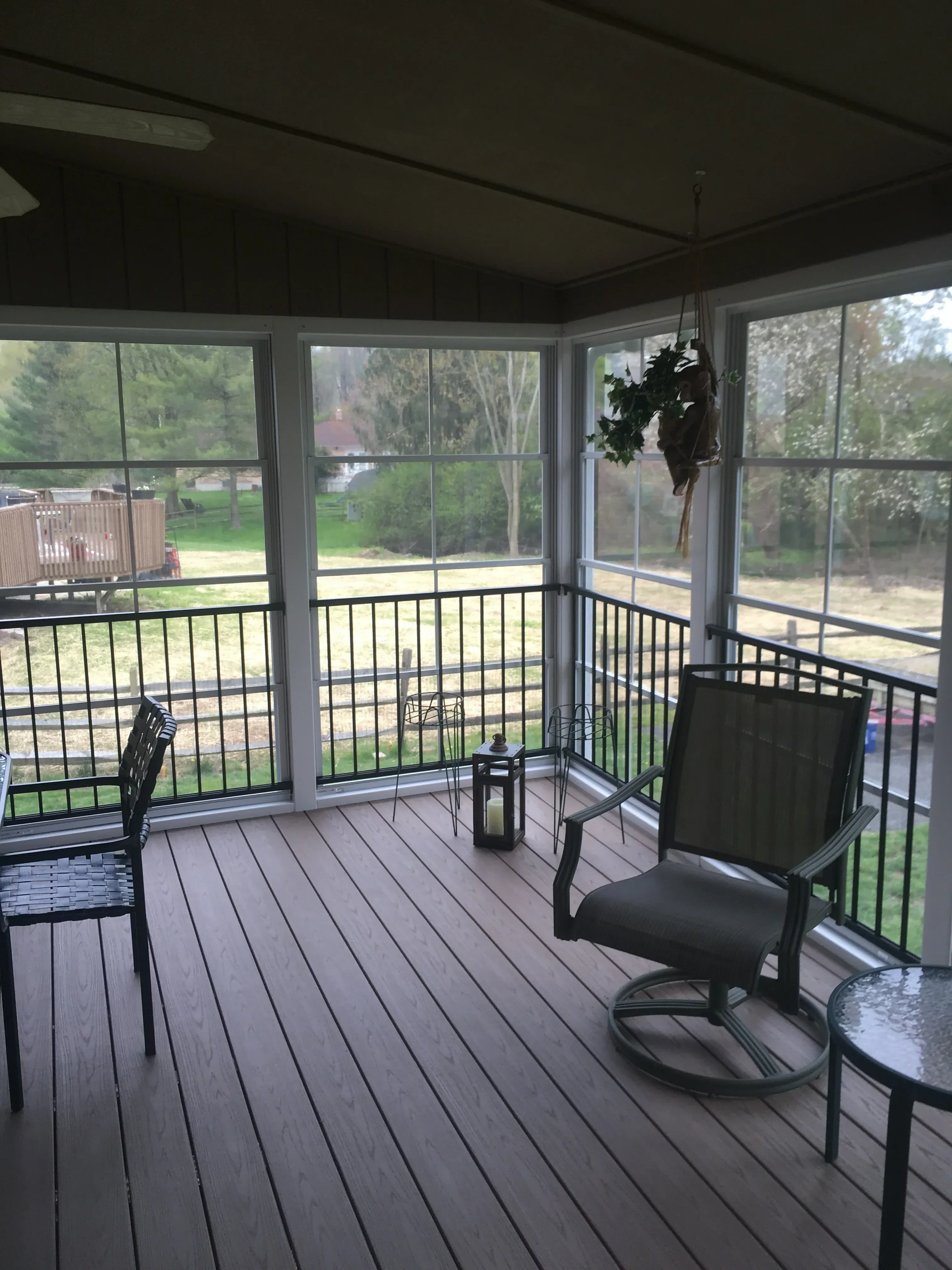 Composite deck with black metal cable railing, glass doors, and horizontal decking boards