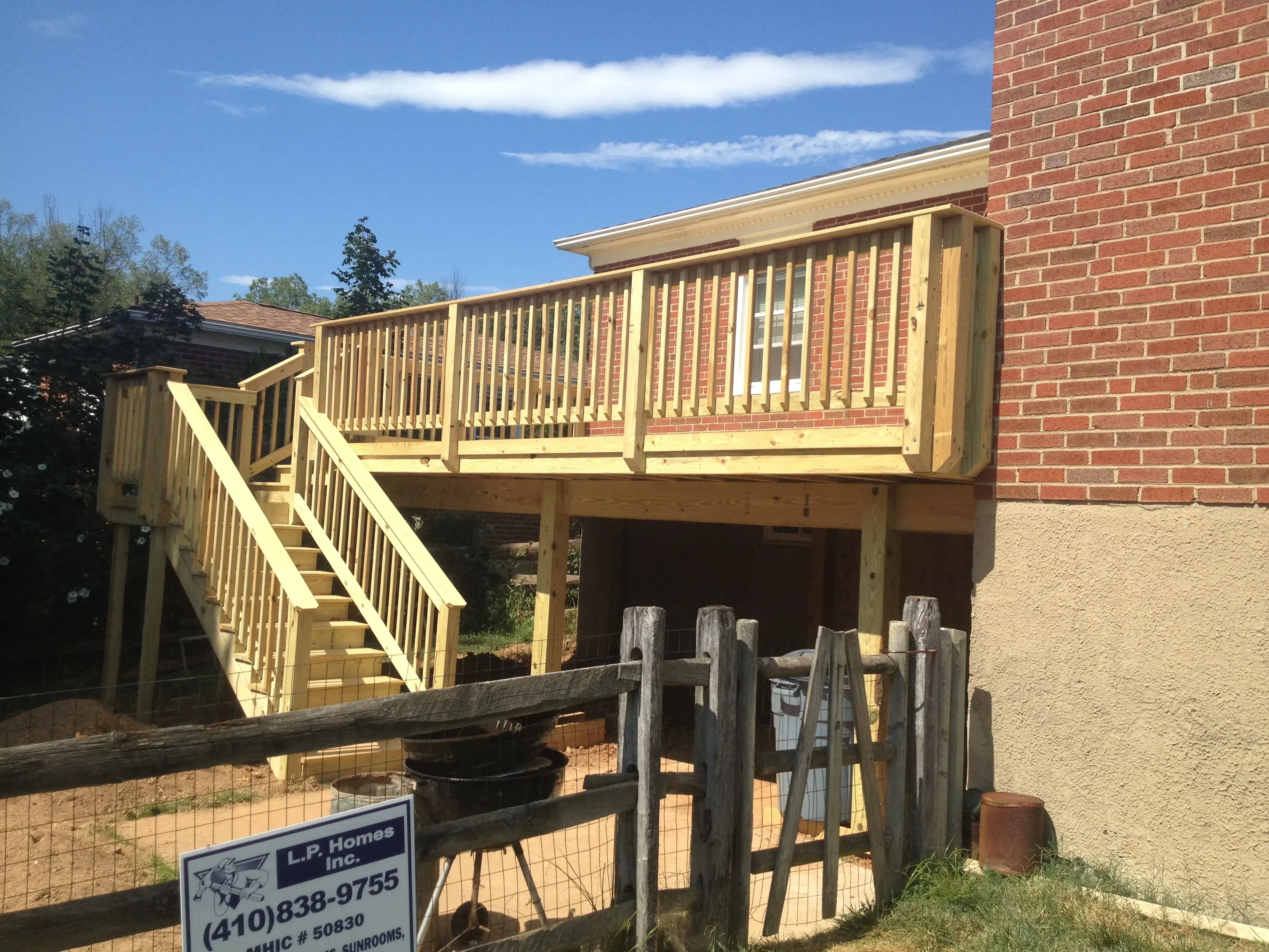 A newly constructed wood-framed deck attached to the rear of a single-family home in Harford County, Maryland. The deck features code-compliant railings and steps leading down to a graded backyard.