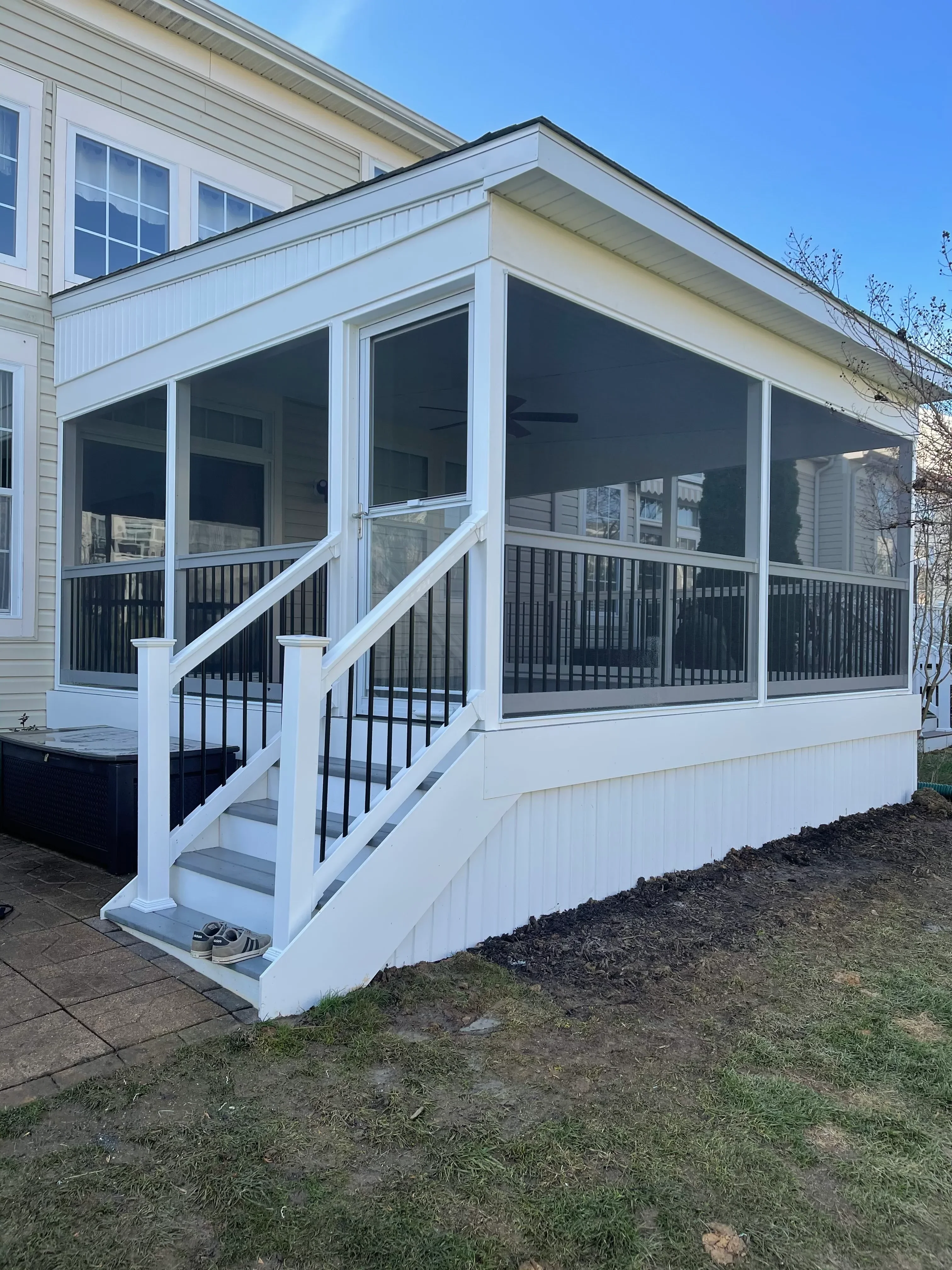A finished four-season sunroom addition on a single-family home in Harford County, Maryland, featuring floor-to-ceiling windows, insulated framing, and a view of a wooded backyard. The interior shows a furnished sitting area with natural light filling the space.